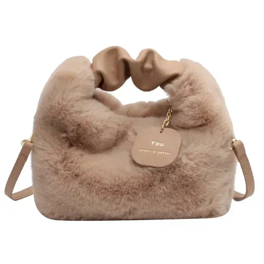 Sac à main en fausse fourrure beige avec anse en cuir, étiquette dorée, design élégant et moderne. Accessoire mode tendance pour femme.