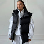 Femme portant un gilet matelassé noir sur un sweat gris, style décontracté et moderne, mode automne-hiver, tendance vestimentaire actuelle.