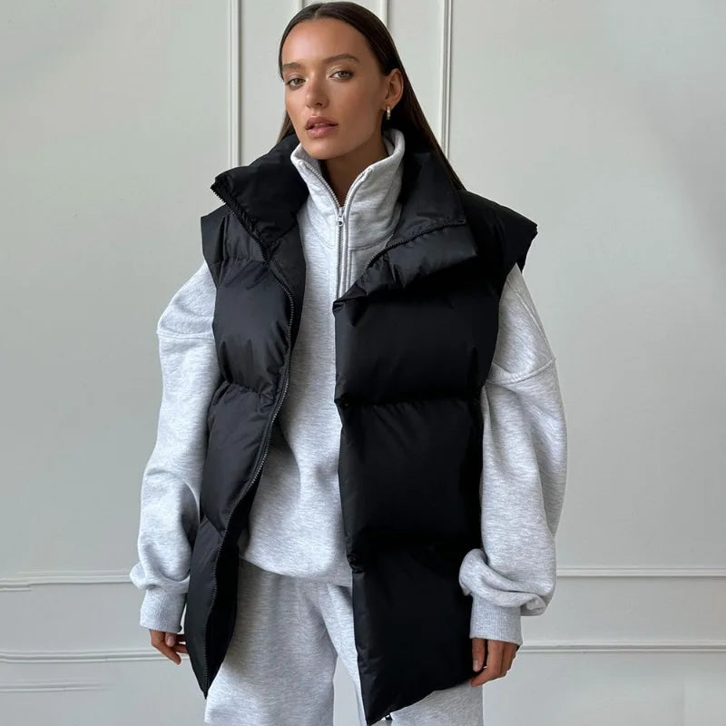 Femme portant un gilet matelassé noir sur un sweat gris, style décontracté et moderne, mode automne-hiver, tendance vestimentaire actuelle.