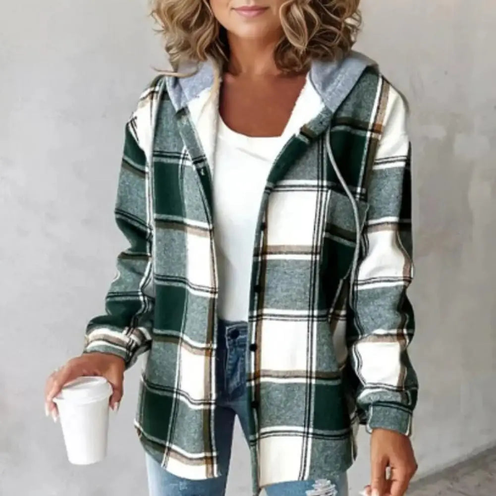Femme portant une chemise à carreaux vert et blanc, tenue décontractée avec jean bleu, tenant un gobelet blanc. Mode automne, style casual chic.