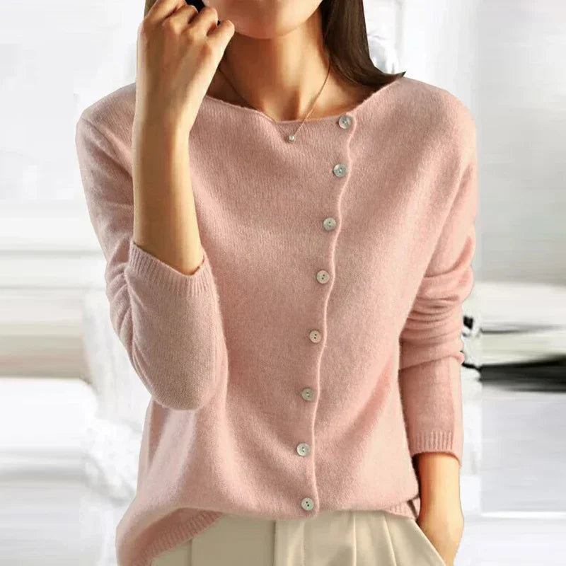 Femme portant un pull rose en cachemire avec boutons, manches longues, col rond. Mode élégante, tenue automne-hiver, style décontracté chic.