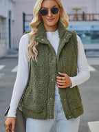 Femme portant un gilet en fausse fourrure vert, lunettes de soleil et pull blanc, mode automne-hiver, style décontracté chic, rue urbaine.