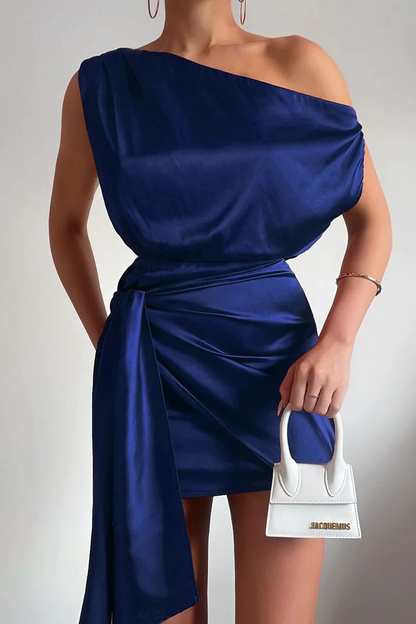 Robe bleue asymétrique élégante avec ceinture, tenue de soirée chic. Sac à main blanc Jacquemus, mode féminine tendance.