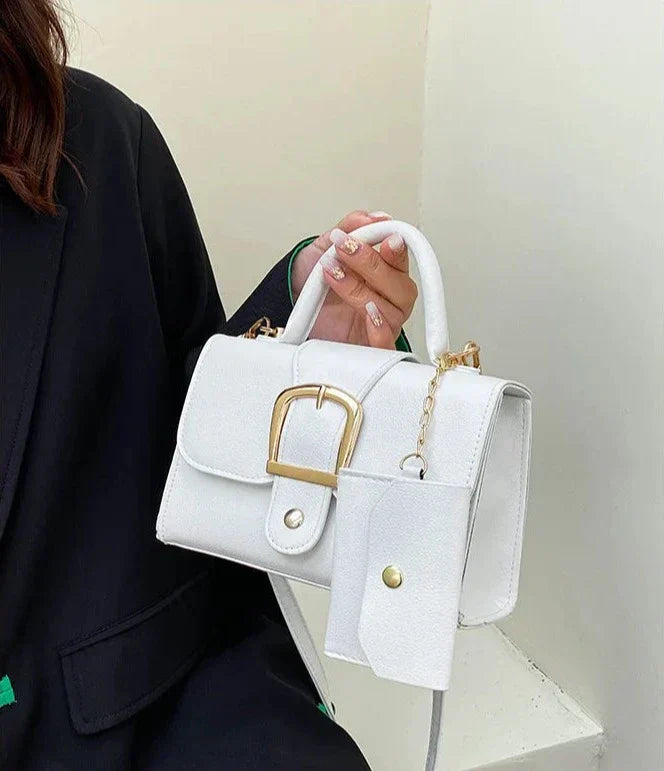 Sac à main blanc élégant avec boucle dorée, porté par une femme en manteau noir. Accessoire mode chic, tendance et moderne pour femmes.