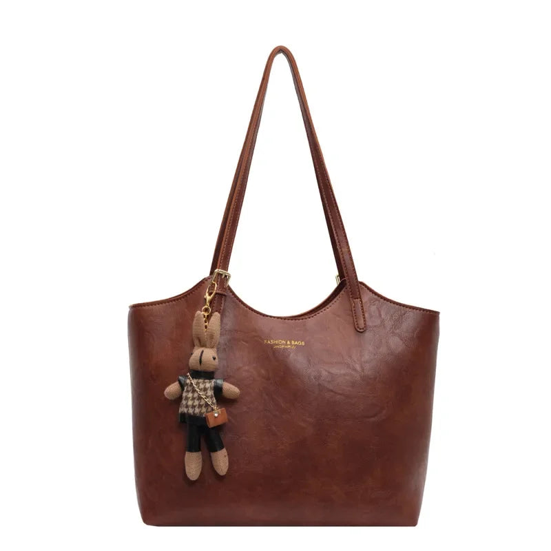 Sac à main en cuir marron avec porte-clés peluche lapin, design élégant, mode femme, accessoire tendance, idéal pour sorties et bureau.