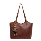 Sac à main en cuir marron avec porte-clés peluche lapin, design élégant, mode femme, accessoire tendance, idéal pour sorties et bureau.