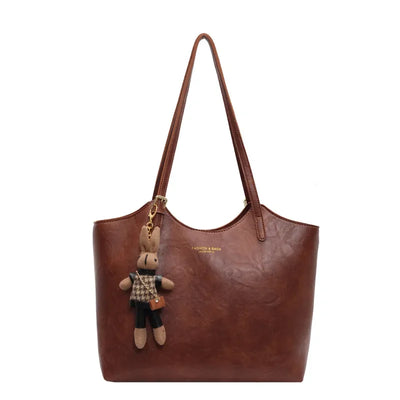Sac à main en cuir marron avec porte-clés peluche lapin, design élégant, mode femme, accessoire tendance, idéal pour sorties et bureau.