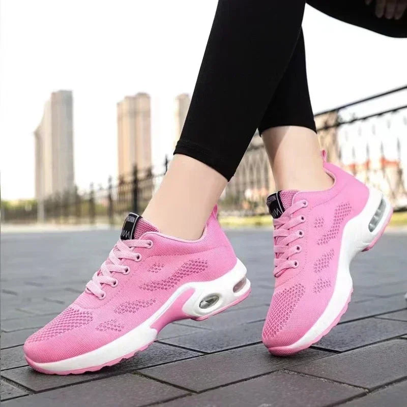 Chaussures de sport roses pour femme avec semelle amortissante, portées en extérieur sur un trottoir urbain. Mode, confort, baskets tendance.