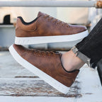 Chaussures en cuir marron pour homme avec semelle blanche, style décontracté, posées sur une surface en bois. Mode masculine, sneakers tendance.