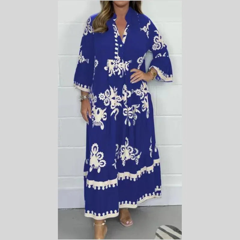 Robe longue bleue à motifs floraux blancs, manches trois-quarts, col en V, portée par une femme. Mode élégante, tendance estivale, tenue chic.