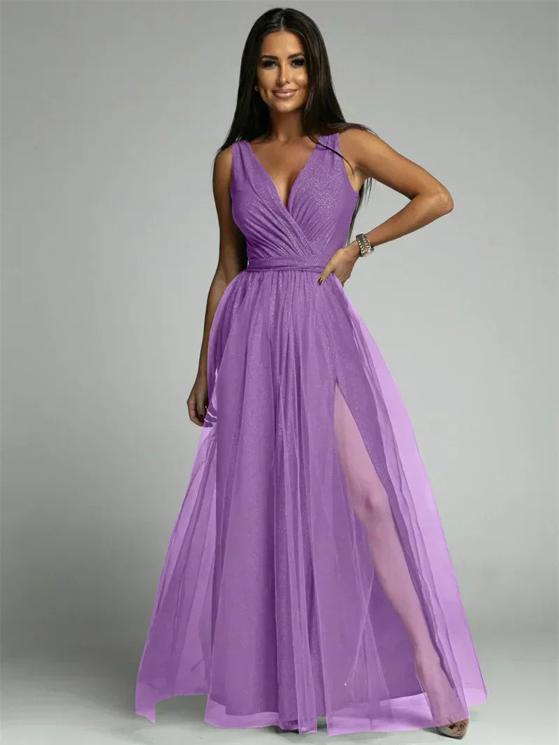 Femme portant une robe de soirée violette élégante avec décolleté en V et fente haute, posant sur fond gris. Mode féminine, tenue de gala.