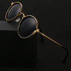 Lunettes de soleil rondes vintage avec monture dorée et verres noirs, posées sur fond noir. Accessoire mode élégant et tendance.