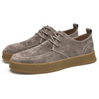 Chaussures en daim gris pour homme avec semelle en caoutchouc marron, style décontracté, lacets, design moderne et confortable.