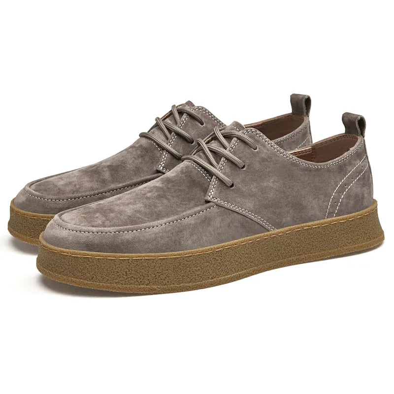 Chaussures en daim gris pour homme avec semelle en caoutchouc marron, style décontracté, lacets, design moderne et confortable.