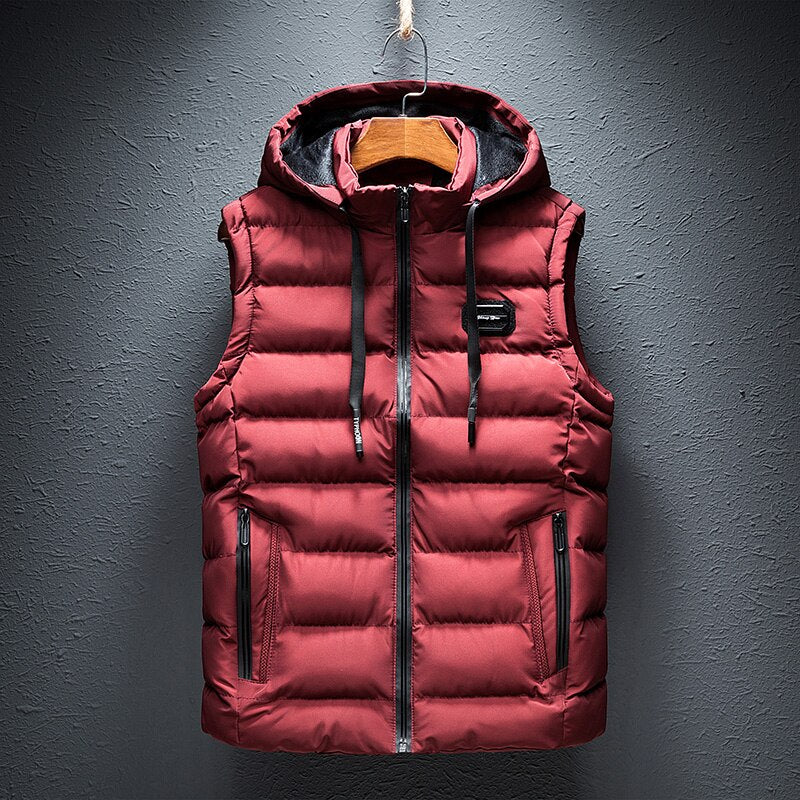 Gilet sans manches rouge avec capuche, fermeture éclair, poches zippées, suspendu sur un cintre. Mode hiver, vêtement chaud, style décontracté.