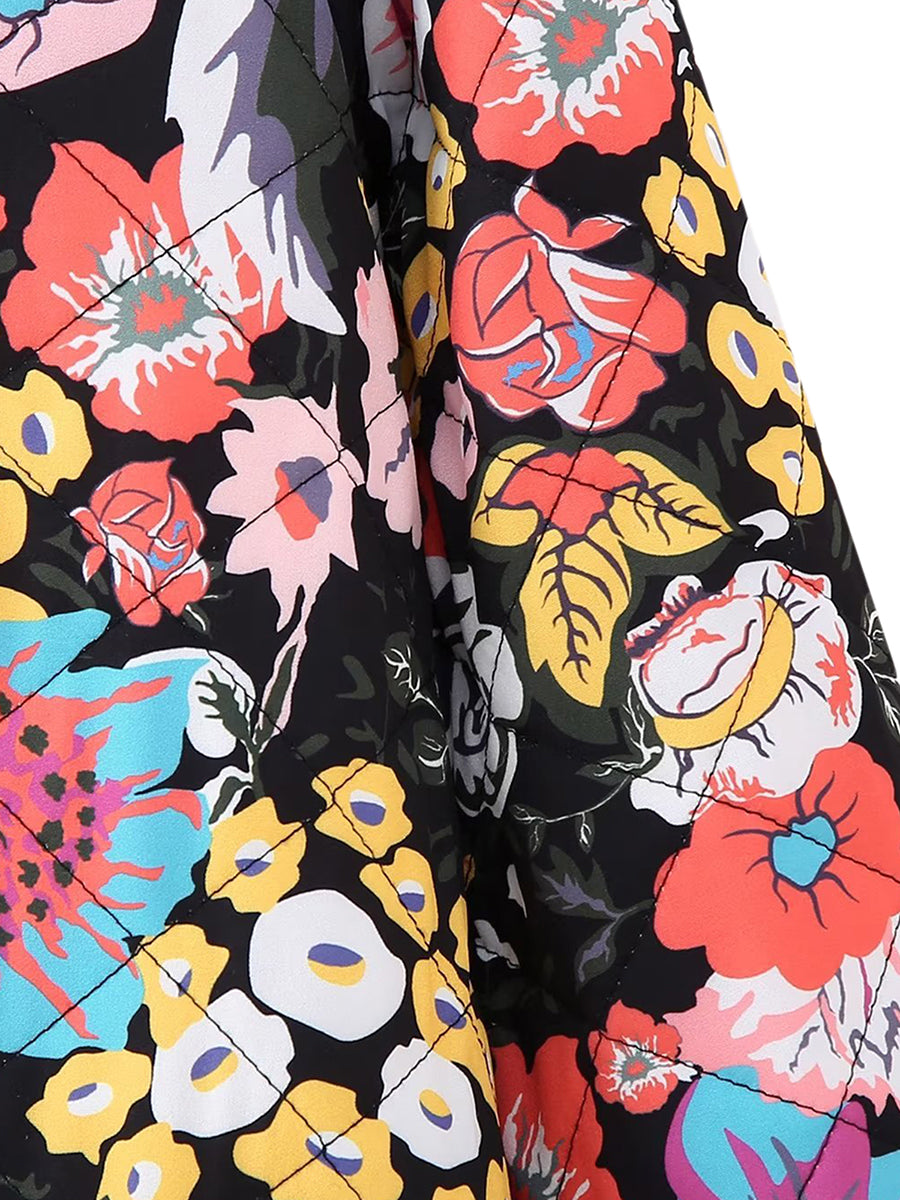 Veste matelassée à motifs floraux colorés sur fond noir, avec des fleurs rouges, jaunes et bleues. Mode tendance, style bohème chic.