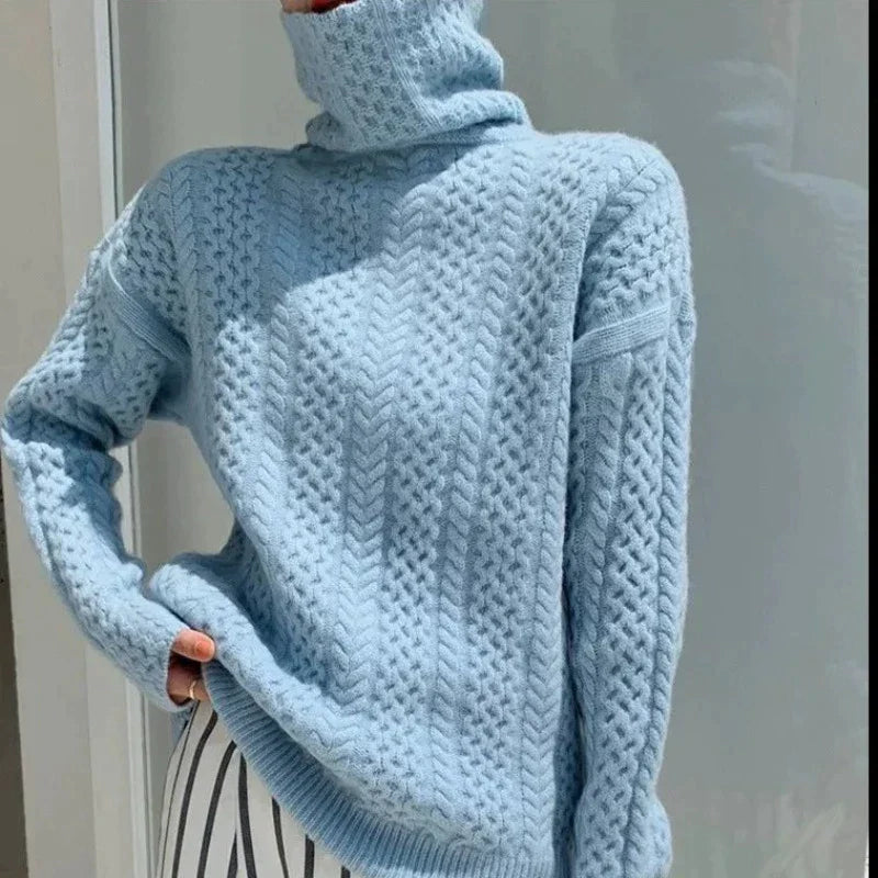 Pull bleu en maille torsadée avec col roulé, porté par une personne. Mode hiver, style décontracté, tendance vêtements chauds.