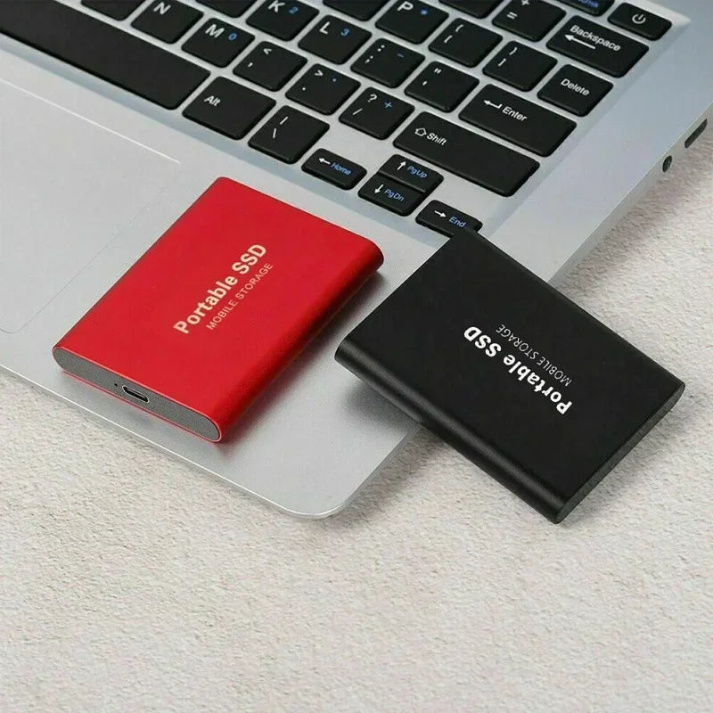 Deux disques SSD portables, rouge et noir, posés sur un ordinateur portable argenté. Stockage externe rapide et compact pour PC.