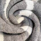 Écharpe en laine grise et blanche, motif rayé, texture douce et chaude, accessoire d'hiver tendance, idéal pour le confort et le style.