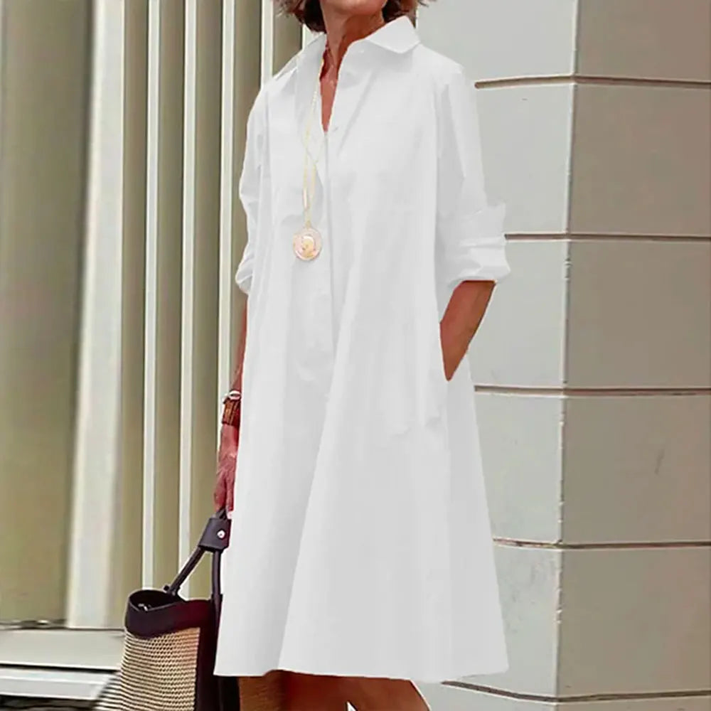 Robe chemise blanche élégante, manches longues, col classique, femme tenant un sac en osier, style décontracté chic, mode féminine moderne.
