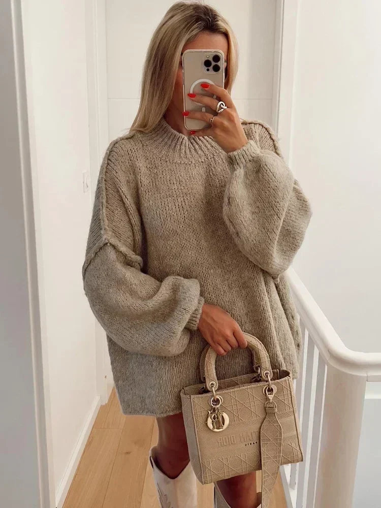 Femme portant un pull oversize beige et tenant un sac à main Dior beige. Mode automne, style décontracté, accessoires de luxe.