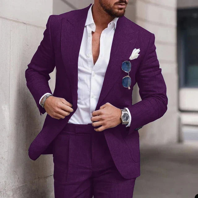 Homme en costume violet élégant, chemise blanche ouverte, lunettes de soleil accrochées, montre-bracelet argentée, style mode urbaine chic.