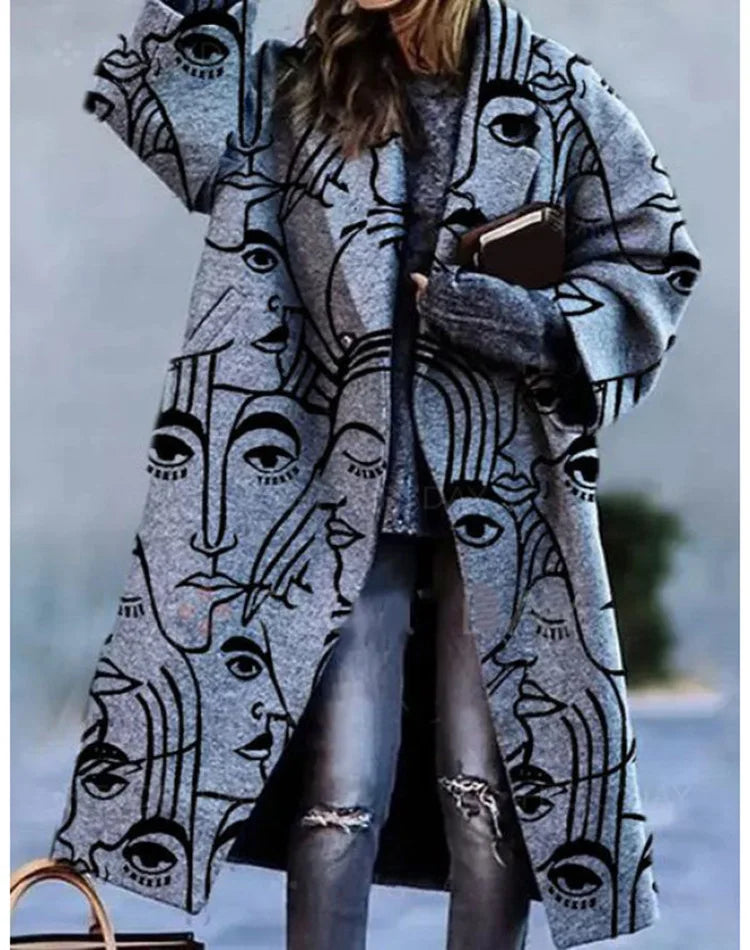 Femme portant un manteau gris à motifs de visages artistiques noirs, style moderne, avec un pull gris et un jean déchiré. Mode automne-hiver tendance.