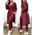 Femme portant un ensemble bordeaux en tricot, composé d'un long cardigan, d'un débardeur et d'un pantalon ajusté, avec des baskets blanches.