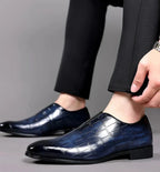 Chaussures habillées en cuir bleu foncé pour homme, motif crocodile, élégantes et modernes, portées avec un pantalon noir.