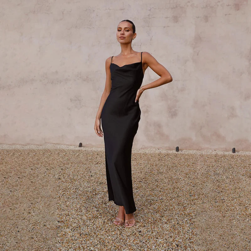 Robe longue noire élégante portée par une femme posant devant un mur texturé, style minimaliste, mode féminine chic, tendance soirée.