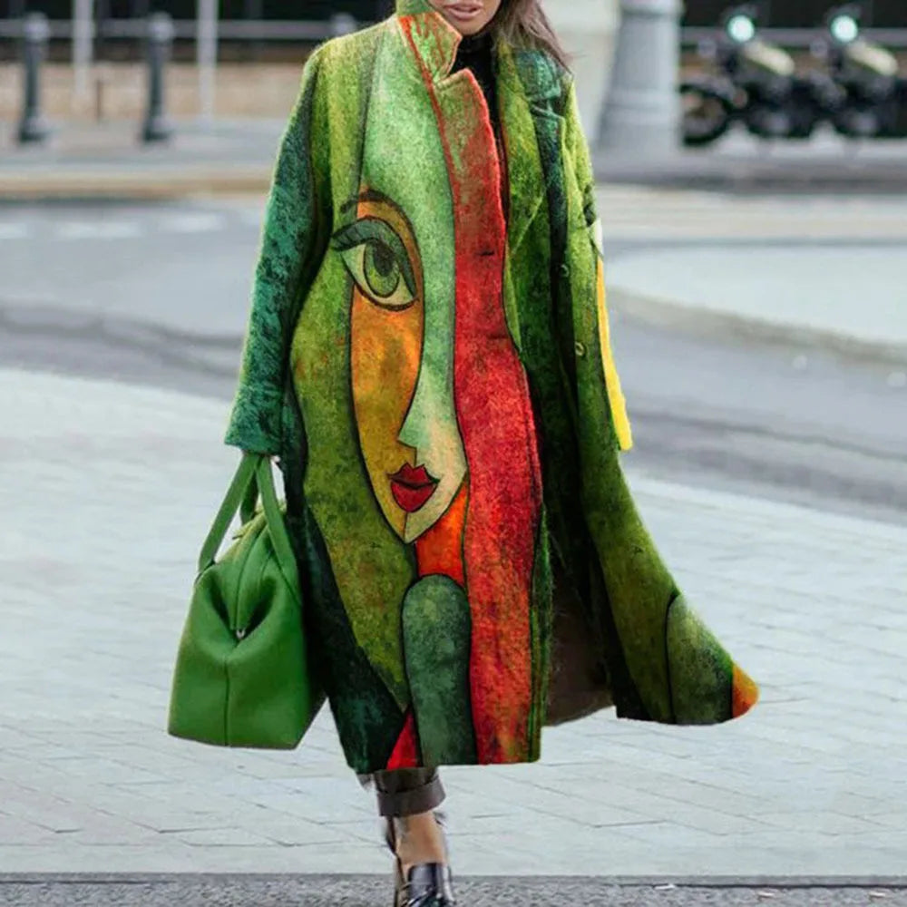 Manteau artistique coloré avec motif visage abstrait, femme tenant un sac vert, rue urbaine en arrière-plan. Mode unique et créative.