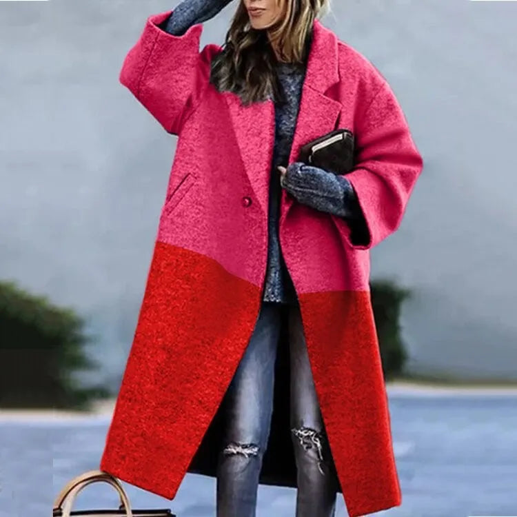Femme portant un manteau long bicolore rose et rouge, avec un pull gris et un jean déchiré, tenant un sac à main et un livre. Mode automne-hiver tendance.