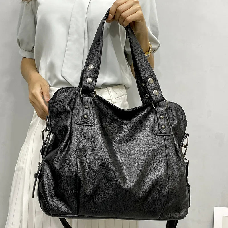 Sac à main en cuir noir élégant, porté par une femme en chemisier blanc. Accessoire mode tendance, idéal pour un look chic et moderne.