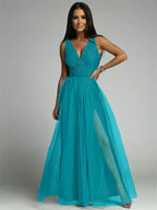 Femme portant une robe de soirée turquoise élégante avec décolleté en V et jupe fluide, posant sur fond neutre. Mode féminine, tenue de gala.