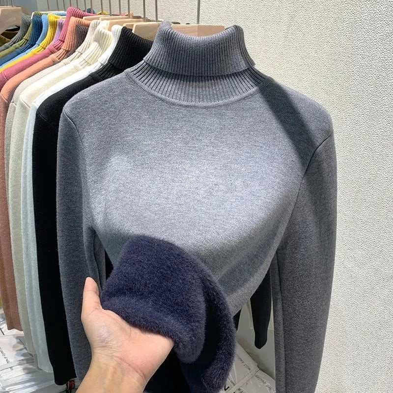 Pulls en laine à col roulé exposés sur un portant, avec une main touchant un pull gris. Vêtements d'hiver, mode féminine, collection automne-hiver.
