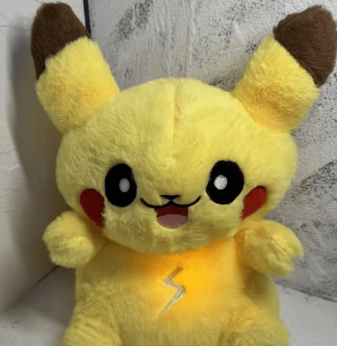Peluche Pikachu jaune avec joues rouges et oreilles marron, éclair lumineux sur le ventre. Jouet Pokémon populaire pour enfants et collectionneurs.