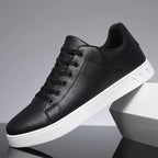 Chaussure de sport noire en cuir synthétique avec semelle blanche, design moderne et minimaliste, idéale pour un look urbain et décontracté.