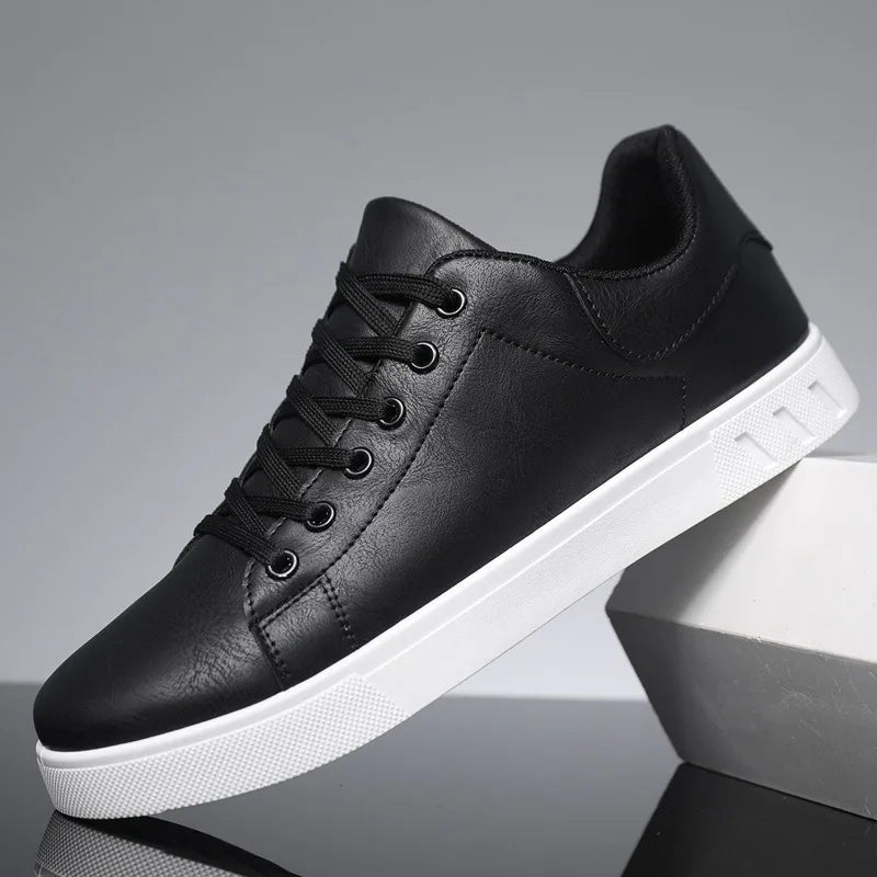 Chaussure de sport noire en cuir synthétique avec semelle blanche, design moderne et minimaliste, idéale pour un look urbain et décontracté.