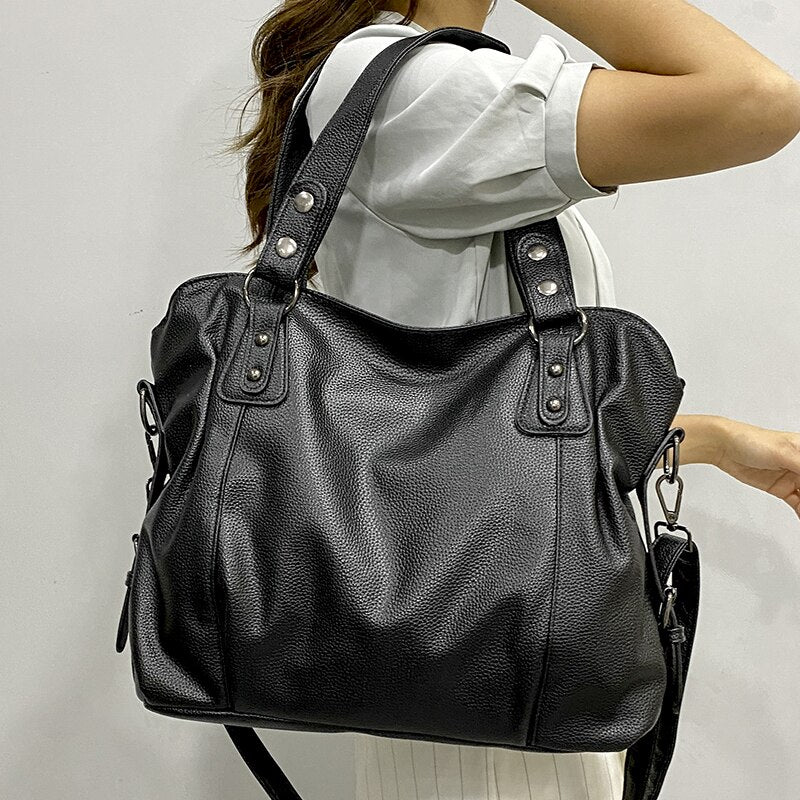 Sac à main en cuir noir porté par une femme en chemise blanche, design élégant avec bandoulière, idéal pour mode féminine et accessoires tendance.