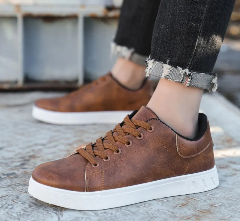 Chaussures en cuir marron pour homme avec semelle blanche, portées avec un jean noir retroussé. Style décontracté et tendance.