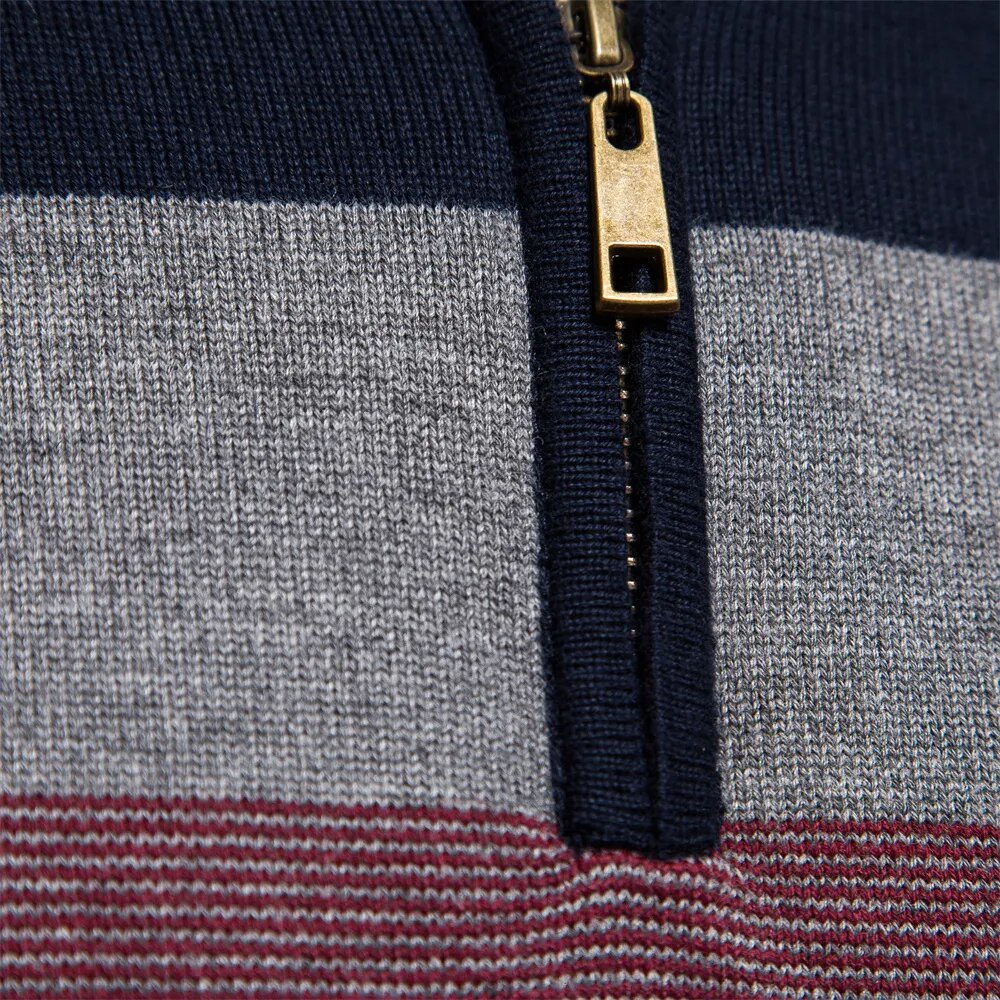 Gros plan sur un pull à rayures bleu marine, gris et bordeaux avec fermeture éclair dorée. Mode automne-hiver, style décontracté chic.