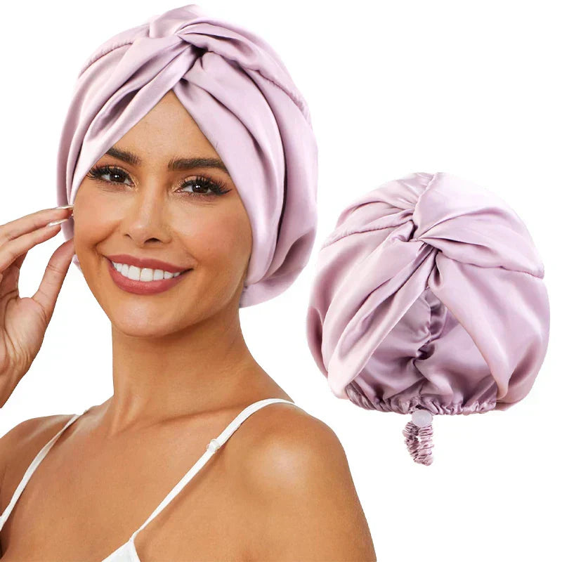Femme souriante portant un turban en satin rose, accessoire de mode élégant pour cheveux, à côté d'un turban similaire sur fond blanc.