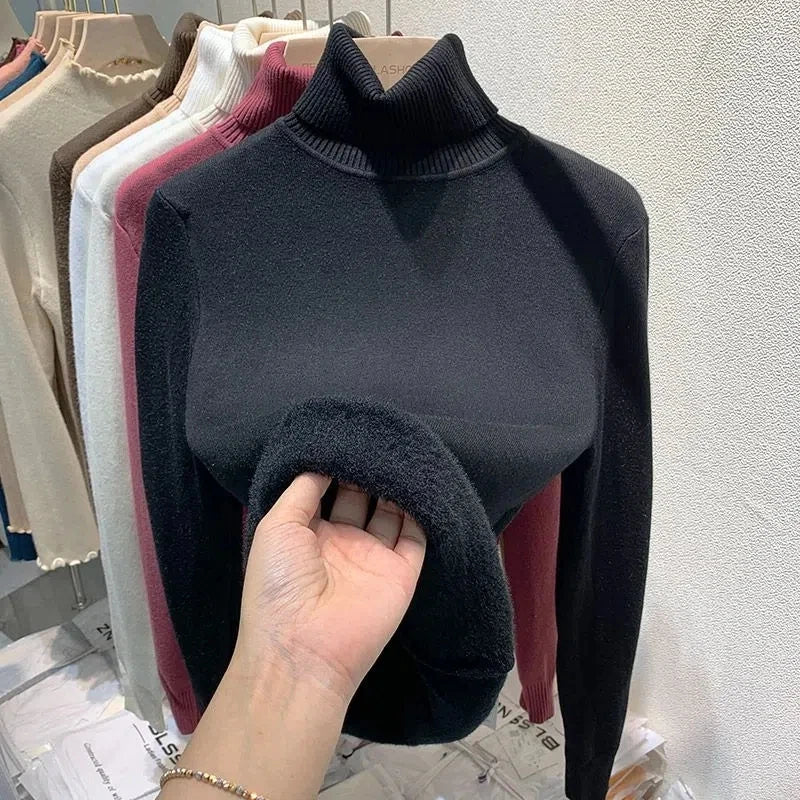 Pull noir à col roulé en laine, exposé sur un cintre, avec une main montrant la texture douce. Vêtements d'hiver élégants et confortables.