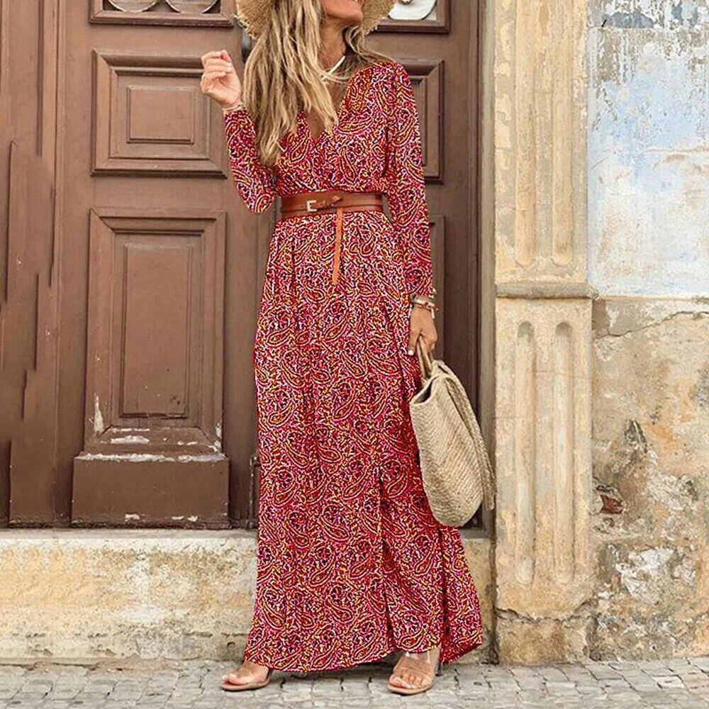 Robe longue bohème rouge à motifs, ceinture marron, femme avec chapeau de paille et sac en osier, devant porte en bois, style estival chic.