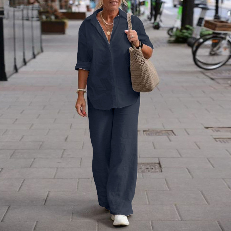 Femme en tenue décontractée bleue, chemise et pantalon ample, marchant sur un trottoir urbain, portant un sac en osier, ambiance de rue animée.
