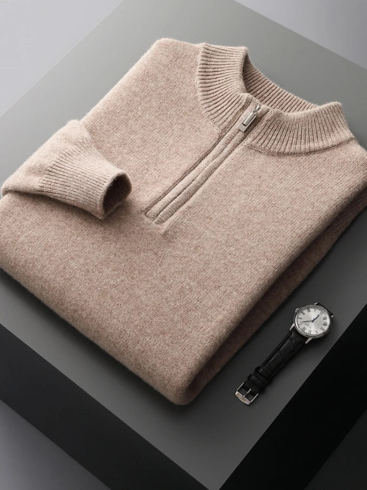 Pull en cachemire beige plié avec fermeture éclair, posé sur une table grise, accompagné d'une montre-bracelet en cuir noir. Mode élégante et luxe.
