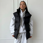 Femme portant un gilet matelassé noir sur un sweat gris, mode automne-hiver, style décontracté et tendance, vêtements confortables et élégants.