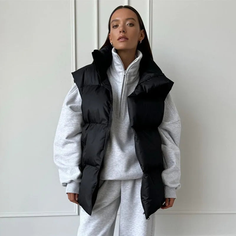 Femme portant un gilet matelassé noir sur un sweat gris, mode automne-hiver, style décontracté et tendance, vêtements confortables et élégants.