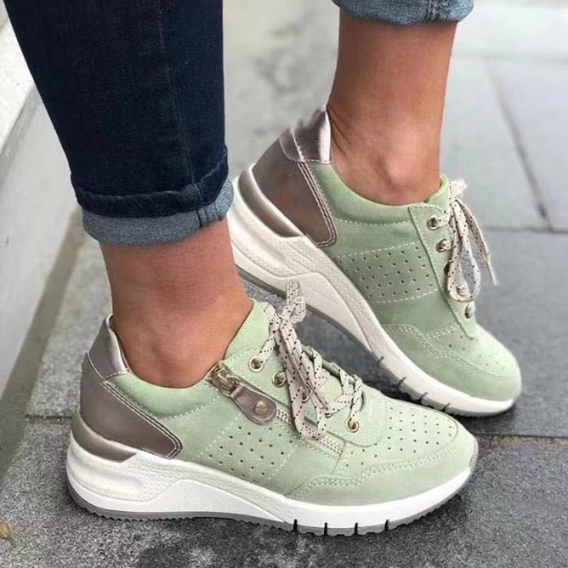 Chaussures de sport vertes pour femme avec semelles épaisses, lacets beiges et détails métalliques, portées avec un jean. Mode tendance et confort.