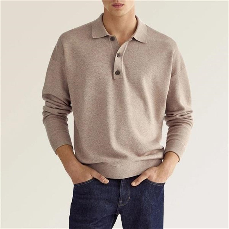 Homme portant un pull polo beige en laine, manches longues, avec boutons, associé à un jean bleu. Mode masculine élégante et décontractée.